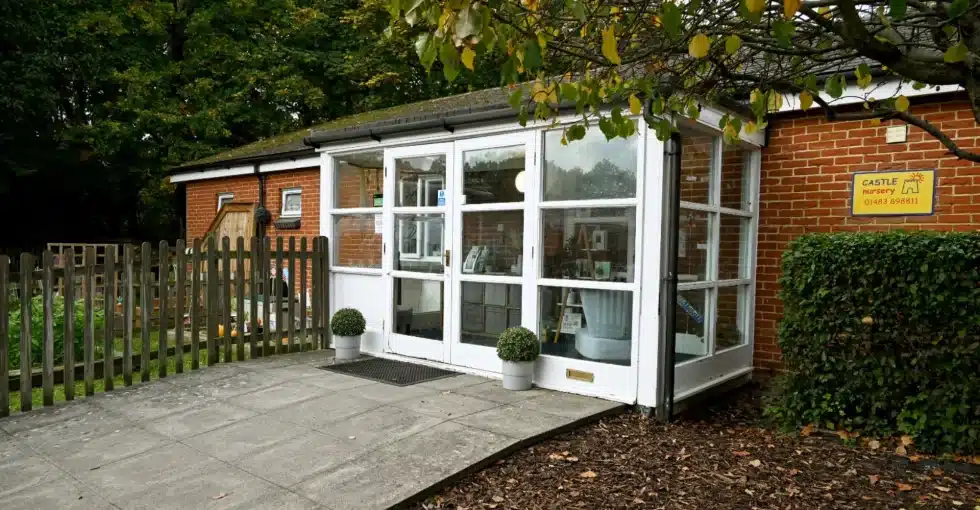 Nursery entrance with glass doors and garden fence.