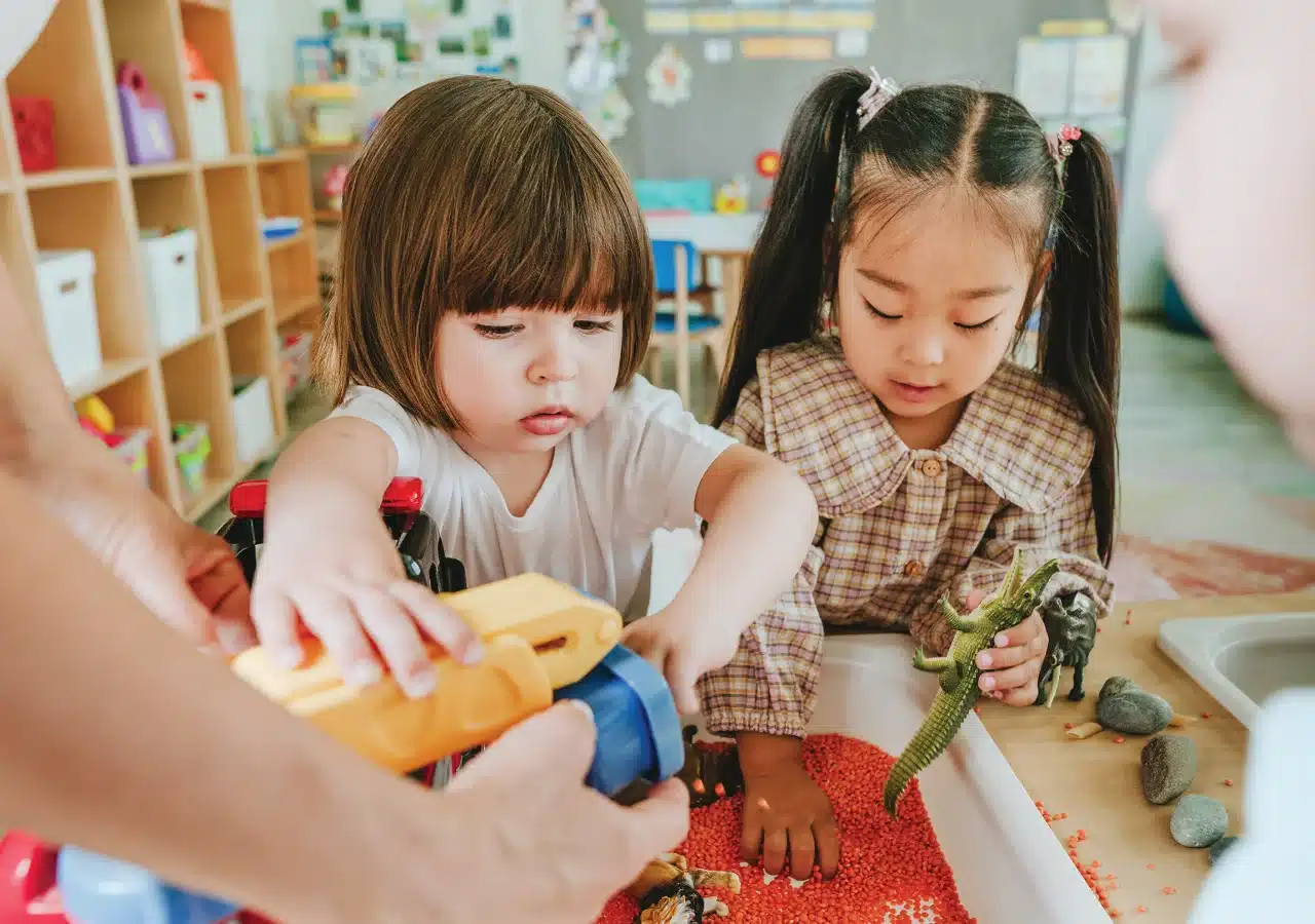 Children playing in tray with various toys.