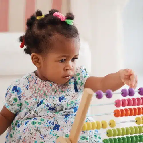Child playing with counter toy in nursery.